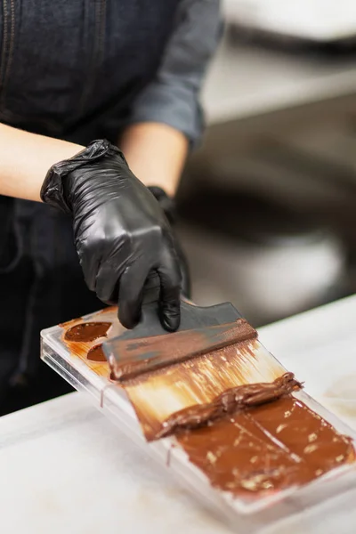 Confectioner in gloves makes chocolates in forms