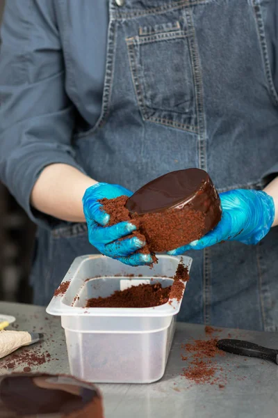 Confectioner makes chocolate cake with icing and cream