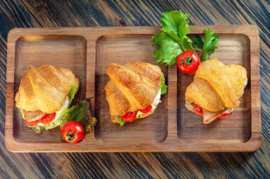 Kremalı kruvasanlar, domatesler ve ahşap kaplama otlar.