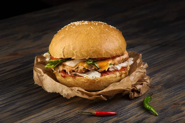 Étvágygerjesztő hamburger hússal és zöldséggel élelmiszerpapíron — Stock Fotó