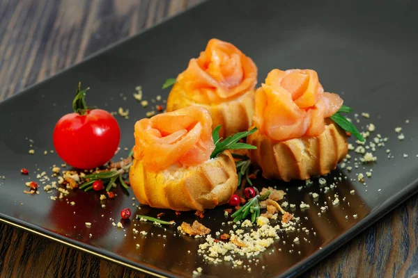 Profiteroles with red fish on a black background — Stock Photo, Image