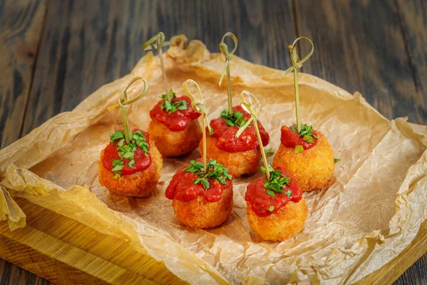 Rice balls with tomato sauce on paper. A wooden background — Stock Photo, Image