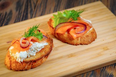 Tahta kesme tahtasındaki balık ve sebzeli sandviç.