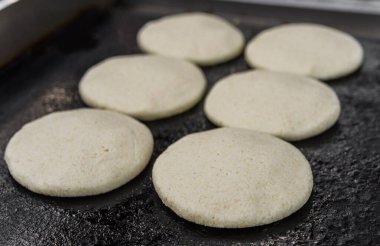 Pişmemiş arepalar, geleneksel Venezuela mısır köfteleri, bir sokak yiyecek pazarında..