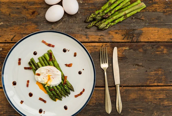 Food photography of a poached egg with asparagus, and crispy bacon.