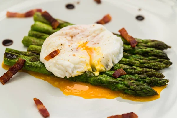 Food photography of a poached egg with asparagus, and crispy bacon.