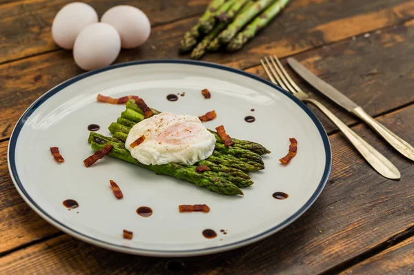 Food photography of a poached egg with asparagus, and crispy bacon.