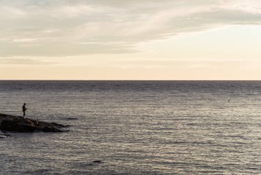 Balıkçılar güzel günbatımı gökyüzü ile kıyıda balık yakalıyor..