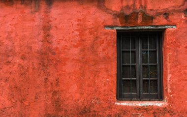 Renkli kırmızı antika pencere ve eski bir binanın duvarı..