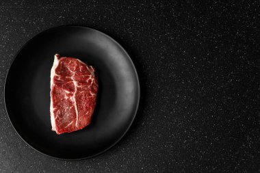 Çiğ sığır eti üst bıçak et biftek siyah taş arka plan karşı.