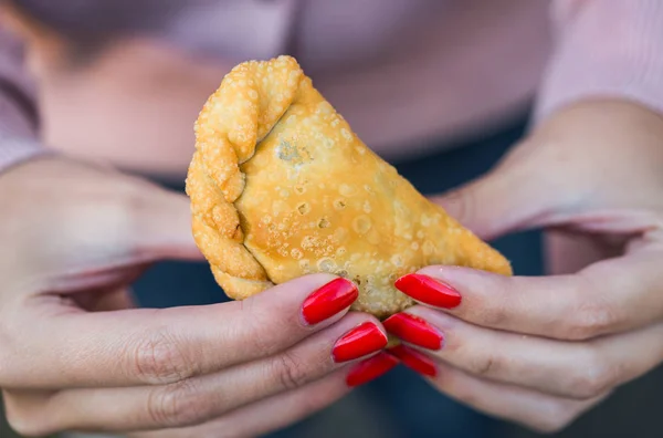 Sokak gıda pazarında geleneksel kızarmış İspanyol ve Arjantin börekleri yemek..