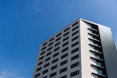 Mavi gökyüzüne karşı modern bir mimari gökdeleni.