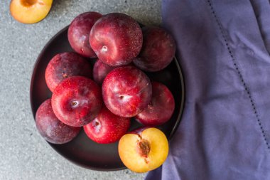 Gri taş zemin üzerinde kırmızı organik erikler.