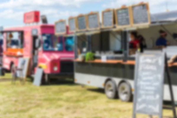 Voedsel vrachtwagens en mensen op een straat voedsel markt festival, wazig met opzet. — Stockfoto