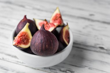 Beyaz ahşap arka plana karşı bir kasede incir yakın.