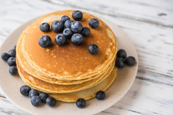 Close up of fluffy pancakes with blueberries against white wooden background. — Stock Photo, Image
