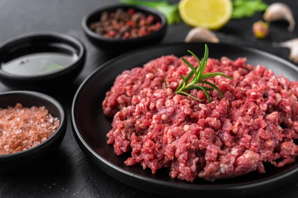 Frisches Hackfleisch Hackfleisch auf schwarzem Teller vor steinerem Hintergrund. — Stockfoto