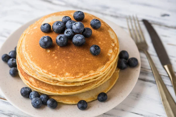 Nahaufnahme von flauschigen Pfannkuchen mit Blaubeeren vor weißem Holzhintergrund. — Stockfoto