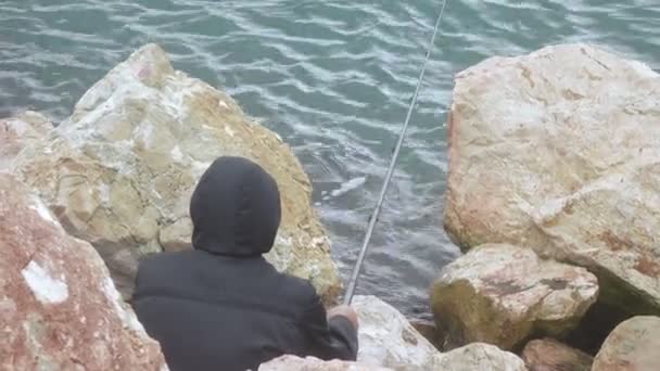 Pescador en el mar sobre rocas — Vídeo de stock