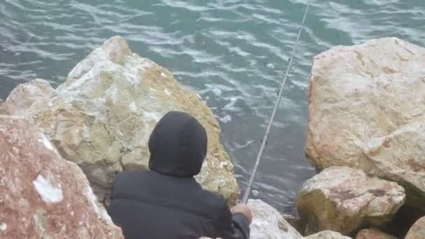 Pescador en el mar sobre rocas — Vídeo de stock