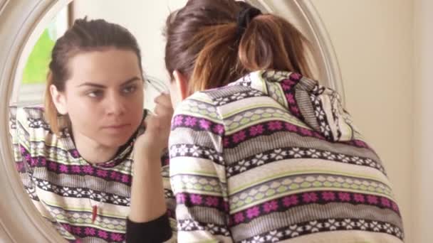 Девушка рисует лицо перед зеркалом — стоковое видео