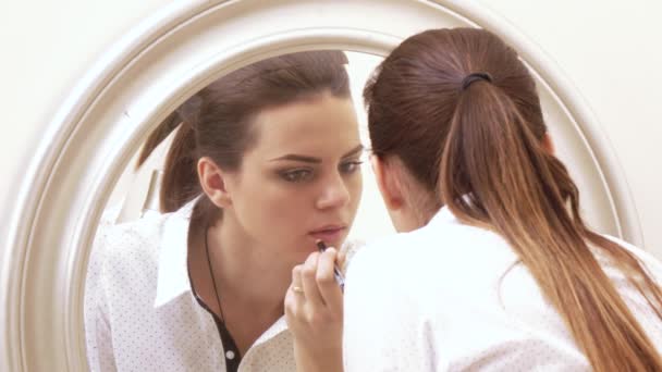 Girl paints face at mirror — Stock Video