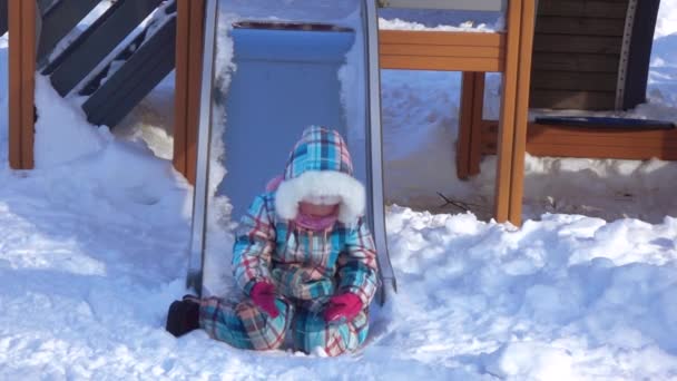 Девочка на детском холме зимой — стоковое видео