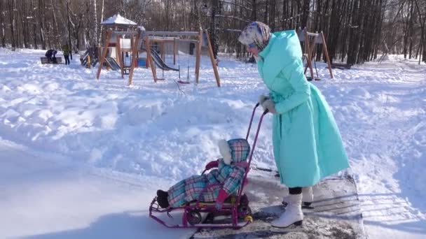 Mamá en patines e hija en trineo — Vídeos de Stock