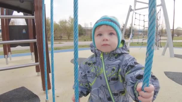 Junge in Overalls auf dem Spielplatz — Stockvideo