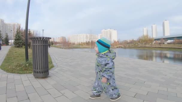 Menino caminha em um parque da cidade — Vídeo de Stock