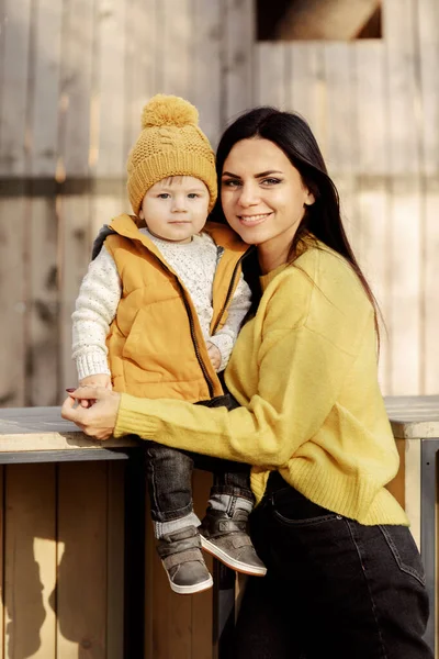 Jovem mãe e bebê se sentam em um banco — Fotografia de Stock