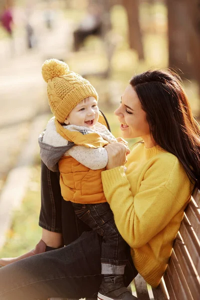 Mladá matka a dítě sedí na lavičce — Stock fotografie