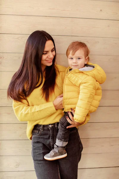 Jonge moeder en baby staan op houten muur — Stockfoto