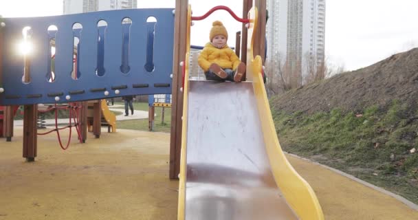 A baba csúszdázik a játszótéren. — Stock videók