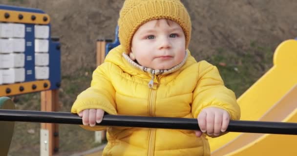 Хлопчик катається на гойдалках на ігровому майданчику — стокове відео