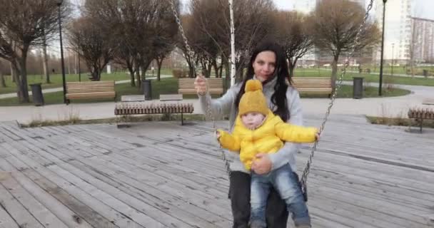 Dziewczyna z dzieckiem potrząsa łańcuchem huśtawka — Wideo stockowe