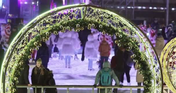 Visitantes de pista de patinaje a través del arco Decoración de Navidad — Vídeo de stock