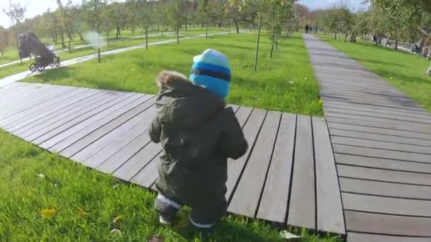 Niño pequeño pisa un césped — Vídeos de Stock