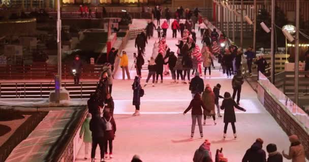 Arka planda buz pateni pisti ziyaretçileri, sahne ve Noel süslemeleri. — Stok video