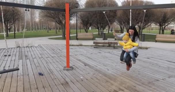 Girl with baby shakes a chain swing — Stock video