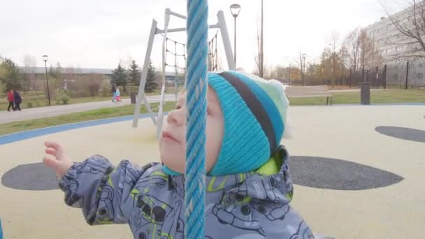 Junge in Overalls auf dem Spielplatz — Stockvideo