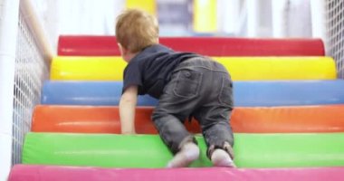 Infant boy plays on a plastic slide