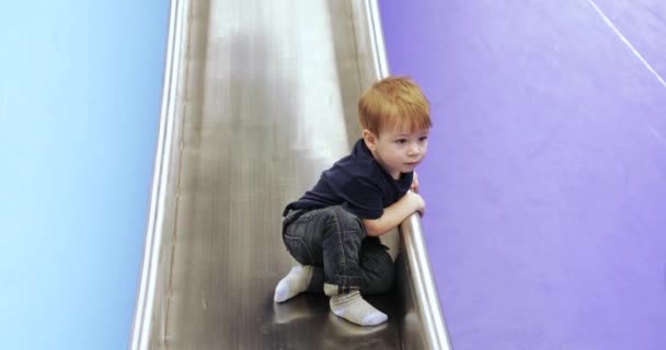 Infant boy plays on a metalic slide — Stockvideo