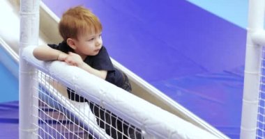 Infant boy plays on a metalic slide