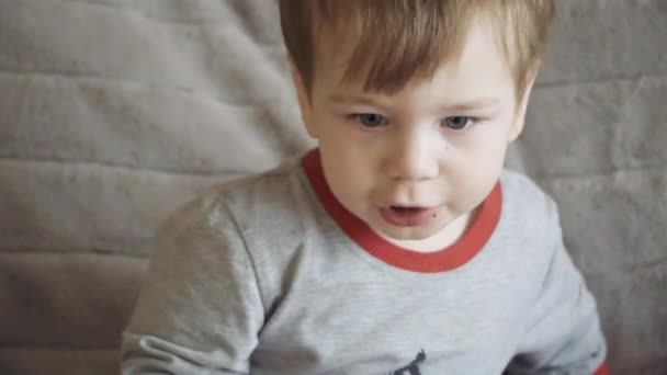 Мальчик на диване ест печенье — стоковое видео