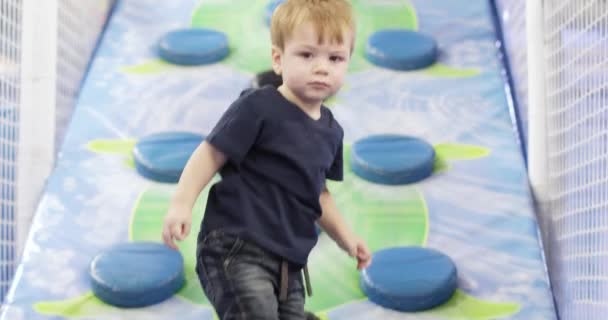 Infant boy plays on a plastic slide — Stockvideo