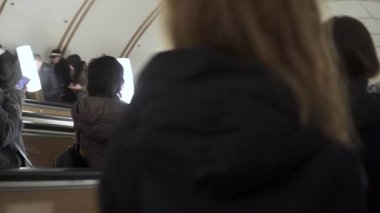 Yolcular Moskova metro istasyonları arasındaki bir yürüyen merdivenden iniyor.