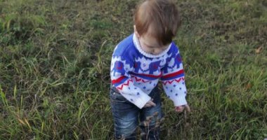 Küçük çocuk kır çiçekleriyle oynuyor.