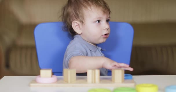 Niño pone un rompecabezas de madera — Vídeo de stock