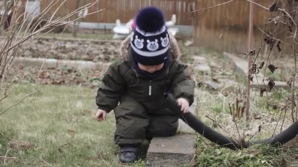 Мальчик в комбинезоне играет с гофрированным — стоковое видео
